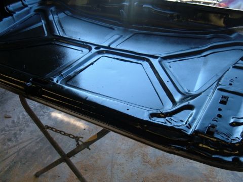 1978 Ford Bronco - The underside of a car hood, recently painted black, is supported by a metal stand.