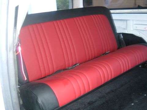 1978 Ford Bronco - The interior features a red and black upholstered rear seat with visible seatbelts and black carpeting.
