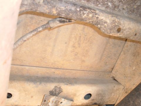 1978 Ford Bronco - The underside of a vehicle shows a fuel line running along the frame, with some rust and dirt present.