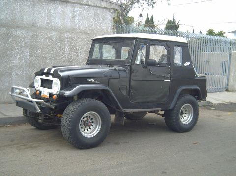 1992 Ford Explorer - This vintage Toyota Land Cruiser is parked on a street with a concrete wall and metal gate in the background.