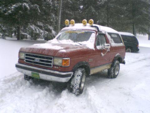 1989 Ford Bronco - 1989 Ford Bronco parked in a snowy area with trees in the background.