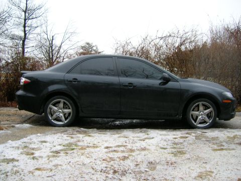 1994 Ford Probe - Side view of a dark sedan with five-spoke alloy wheels parked on a snowy surface.