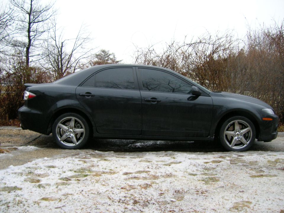 Dark sedan, side view. Five-spoke alloy wheels