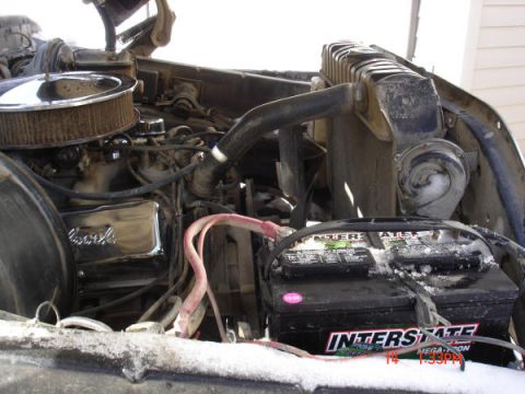 1979 Ford Bronco - Close-up view of the engine compartment, showing the battery, air filter, and radiator with snow accumulation.