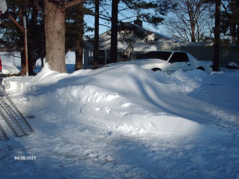 1995 Ford Probe - A white coupe is almost completely covered by a large snowdrift after a heavy snowfall.