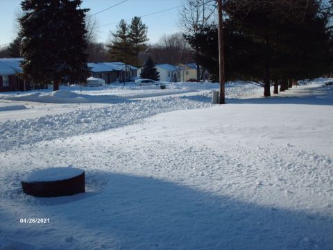 1995 Ford Probe - A winter scene shows a street covered in snow, with houses and trees lining the road under a clear sky.