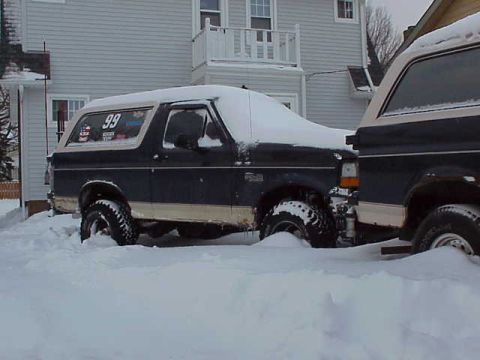 1993 Ford Bronco - Two Ford Broncos are partially buried in snow, suggesting a recent snowfall.