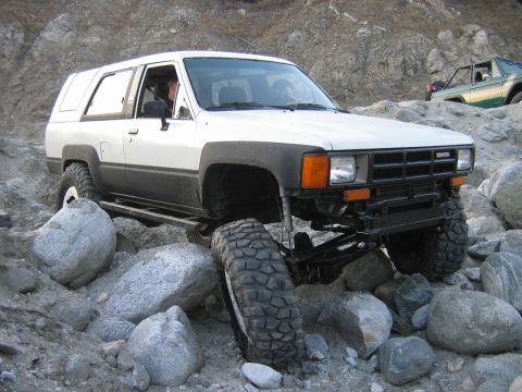 1985 Toyota 4Runner - White 1985 Toyota 4Runner tackling a difficult rocky off-road course with a second vehicle in the background.