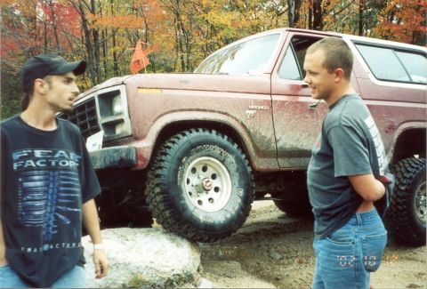 1980 Ford Bronco - Two men stand next to a red Ford Bronco, which is positioned on rocks during an off-road excursion.