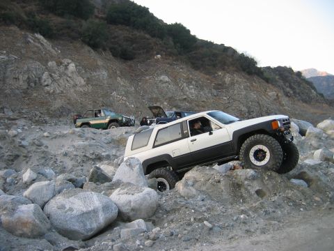 1985 Toyota 4Runner - Multiple off-road vehicles traverse a rocky mountain path.