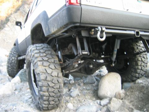 1985 Toyota 4Runner - Modified 1985 Toyota 4Runner's rear suspension and axle are visible while navigating rocky terrain.