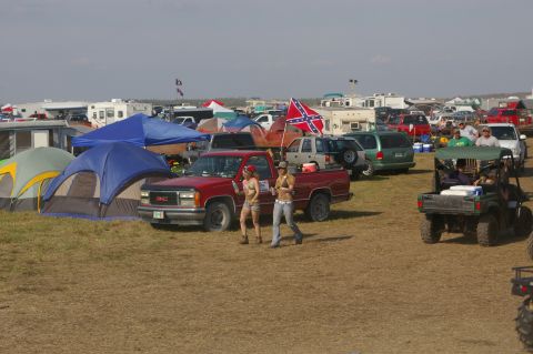 1974 Ford F-100 - A red GMC pickup truck is parked in a field with tents and other vehicles.
