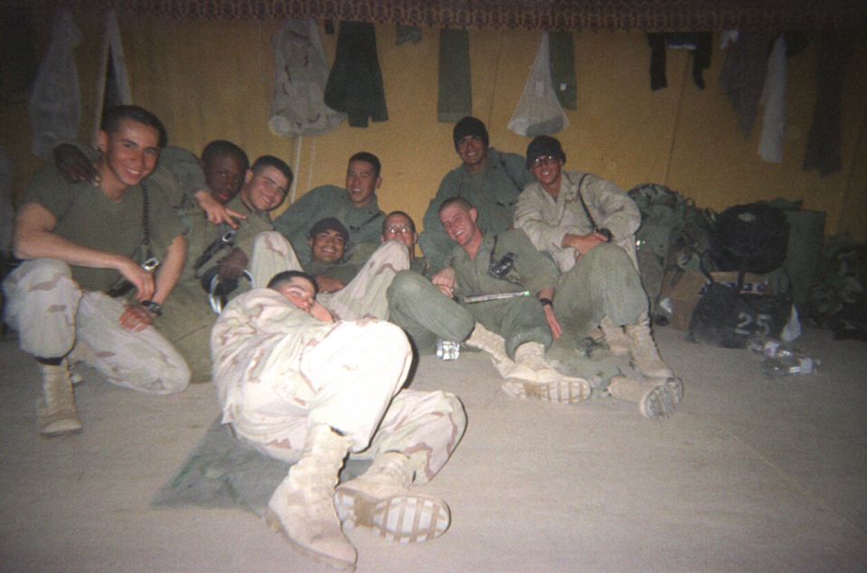 Group of soldiers in a tent, one with "25" on a bag