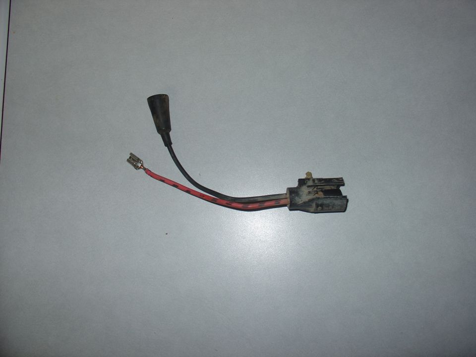 Electrical connector with red and black wires and a black rubber boot on a gray surface