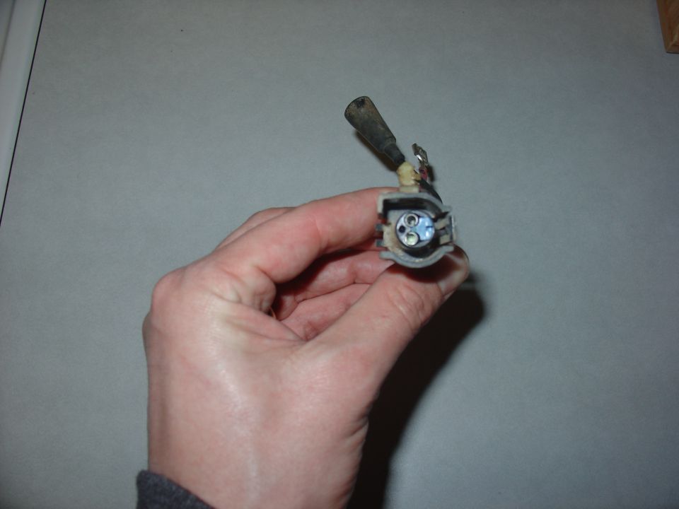 Hand holding an electrical connector with three pins visible