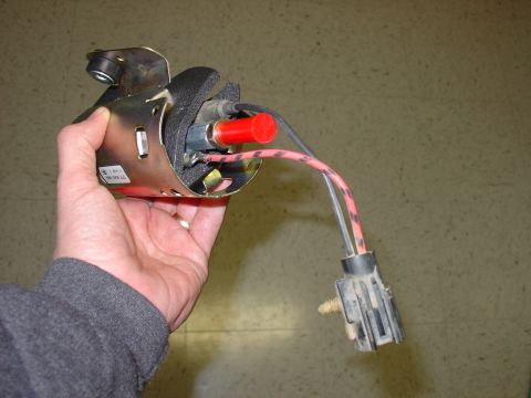 1988 Ford Bronco - A person holds a vehicle fuel pump assembly, showing its electrical connector and red cap detail.