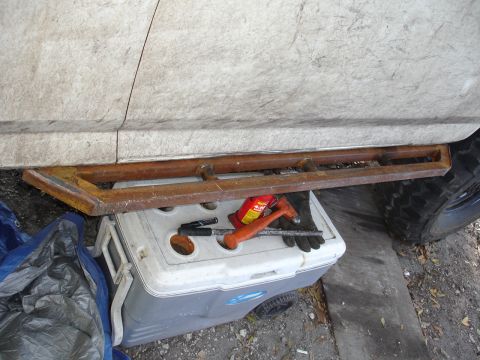 1989 Ford Bronco - Custom rock sliders are installed on the side of a vehicle, with a cooler and tools placed beneath.