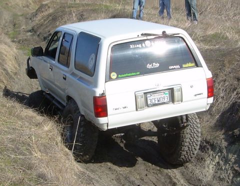 1993 Toyota 4Runner - White 1993 Toyota 4Runner navigating a muddy off-road trail with lifted suspension and large tires.