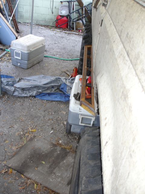 1989 Ford Bronco - A vehicle is parked in a cluttered outdoor area, with coolers and tarps nearby.