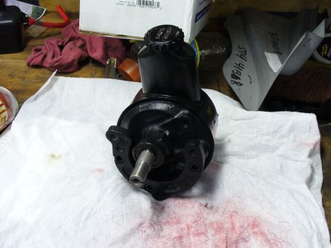 1978 Ford Bronco - Power steering pump part shown on a workbench with various automotive items.