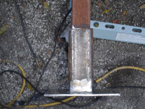 1989 Ford Bronco - A metal post is shown with visible welding and a base plate, surrounded by electrical cords and a level.