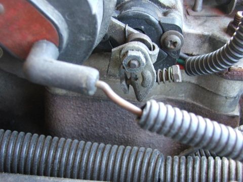 1985 Ford Crown Victoria LTD - This image shows a close-up view of a vehicle's throttle linkage system, including a wire and spring mechanism.