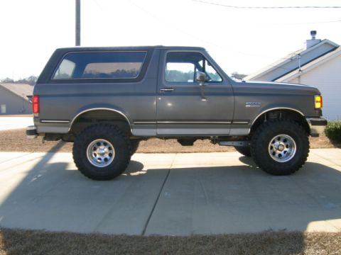 1989 Ford Bronco - This lifted Ford Bronco is shown from its side profile, parked on a concrete surface.