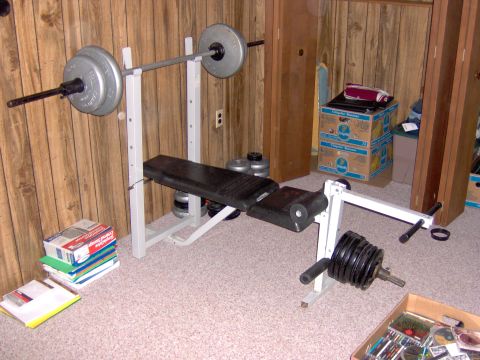 1996 Chevrolet Cavalier - A weight bench setup is shown with a barbell and various weight plates, along with other exercise equipment.