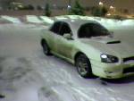 Silver Subaru Impreza sedan with hood scoop in snowy lot at night