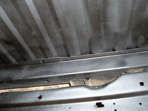 1978 Ford Bronco - Underside of a vehicle showing frame rails and ribbed metal, likely after undercoating application.