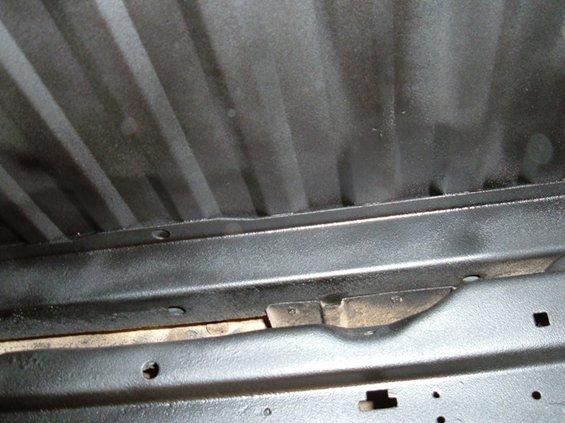 Underside of a vehicle with ribbed metal and frame components visible