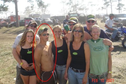 1974 Ford F-100 - Group photo of eight people in matching tank tops and caps posing at an outdoor mud-bogging event, with one person circled in red marker. A…