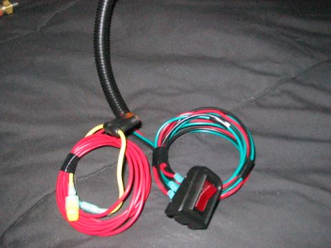 1991 Ford Bronco - A wiring harness with a red switch and multiple colored wires is shown against a dark background.