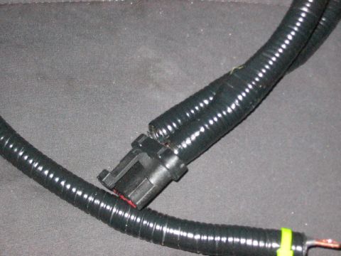 1991 Ford Bronco - A close-up view of a damaged black wiring harness with a disconnected connector.