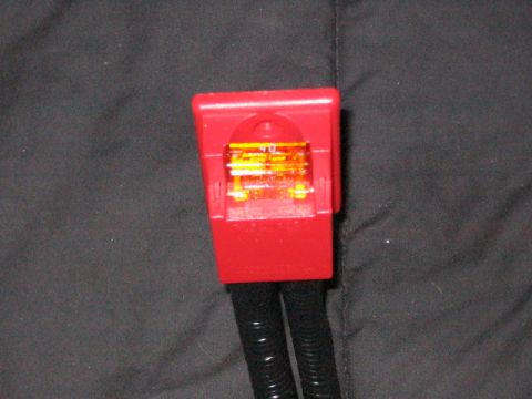1991 Ford Bronco - A close-up view of a red fuse holder connected to two black wires against a dark background.