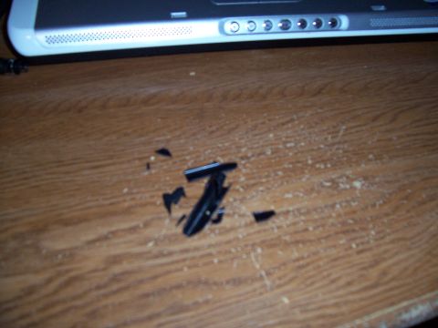 2003 Ford Ranger - Scattered fragments of black plastic lie on a wooden surface, with a laptop visible in the background.
