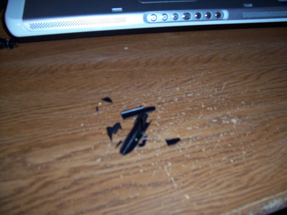 Pieces of black plastic and wood shavings on a desk next to a laptop