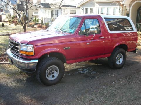 1995 Ford Bronco - Side view of a red 1995 Ford Bronco with a white removable top.
