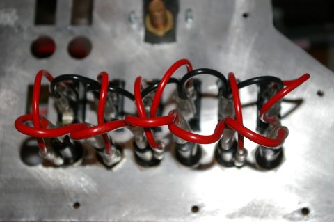 1986 Ford Bronco - A close-up view shows a wiring harness with red and black wires connected to a metal panel, likely part of a vehicle's interior console.