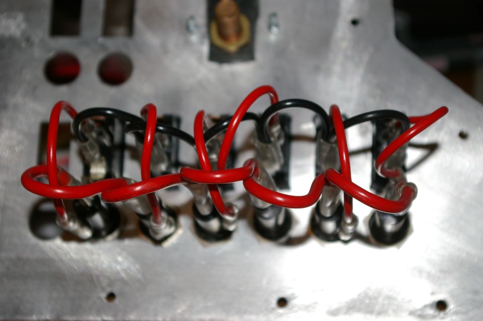 Close-up of red and black wires connected to a metal panel