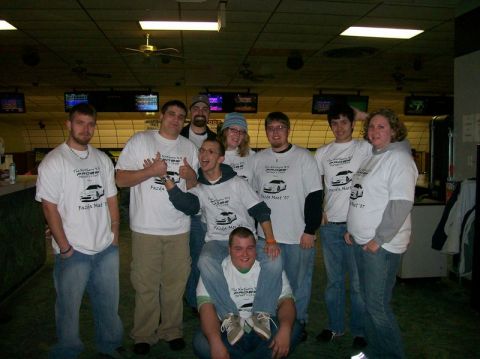 1995 Ford Probe - A group of friends gathered in a bowling alley, all sporting matching t-shirts with a car illustration and event details.
