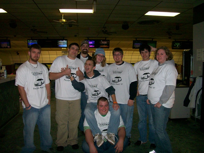 Group of people in a bowling alley, most wearing t-shirts with a car graphic and text that says 'Fazda Mart '07'