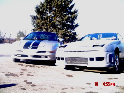 1995 Ford Probe - Two sports cars, a silver 1995 Ford Probe and a white custom vehicle, are parked outdoors on a sunny day.