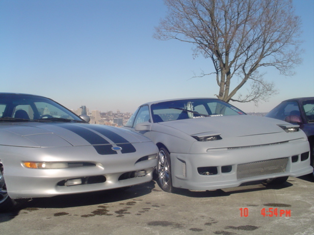 Two silver Ford Probes parked side-by-side, one with black racing stripes