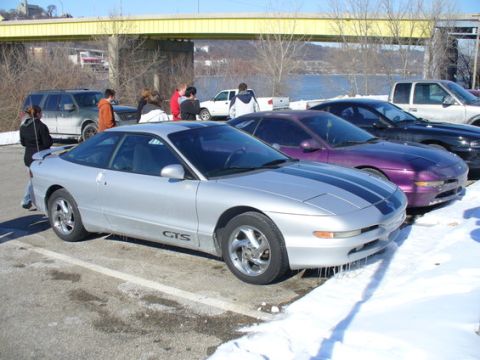 1995 Ford Probe - A silver Ford Probe GTS with dual black racing stripes is parked in the snow next to other vehicles.