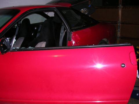 1996 Ford Probe - The driver's side window of a red 1996 Ford Probe is broken, revealing the interior and seats.