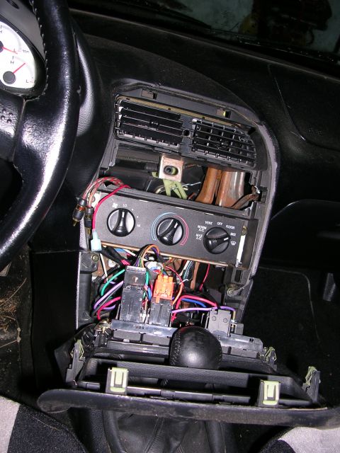 1996 Ford Probe - The interior of a car with the center console removed, revealing exposed wiring and climate control components.