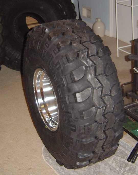 Mud-terrain tire on polished aluminum wheel standing indoors on carpet