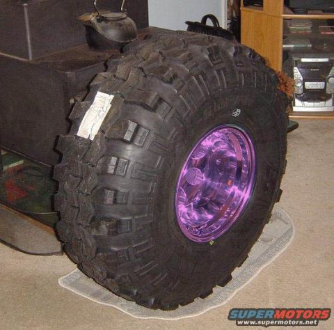1989 Ford Bronco - A close-up of a large, knobby tire with a custom purple wheel is the main focus.