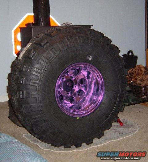 1989 Ford Bronco - A large off-road tire with a distinctive purple chrome rim is shown, with a Supermotors.net logo visible at the bottom right.